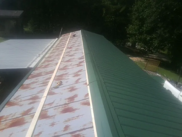 Old rusted panels beside newly installed green metal roofing — Wind Damage Roof Repair by Roofing Brothers in Berryville