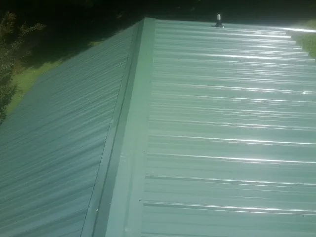 New green metal panels meeting at the ridge of a roof — Flat Roof Repair work by our crew in Berryville