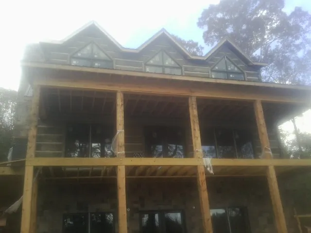 Dormers and porch framing on a large log home under construction — Roof Coating work by our crew in Berryville