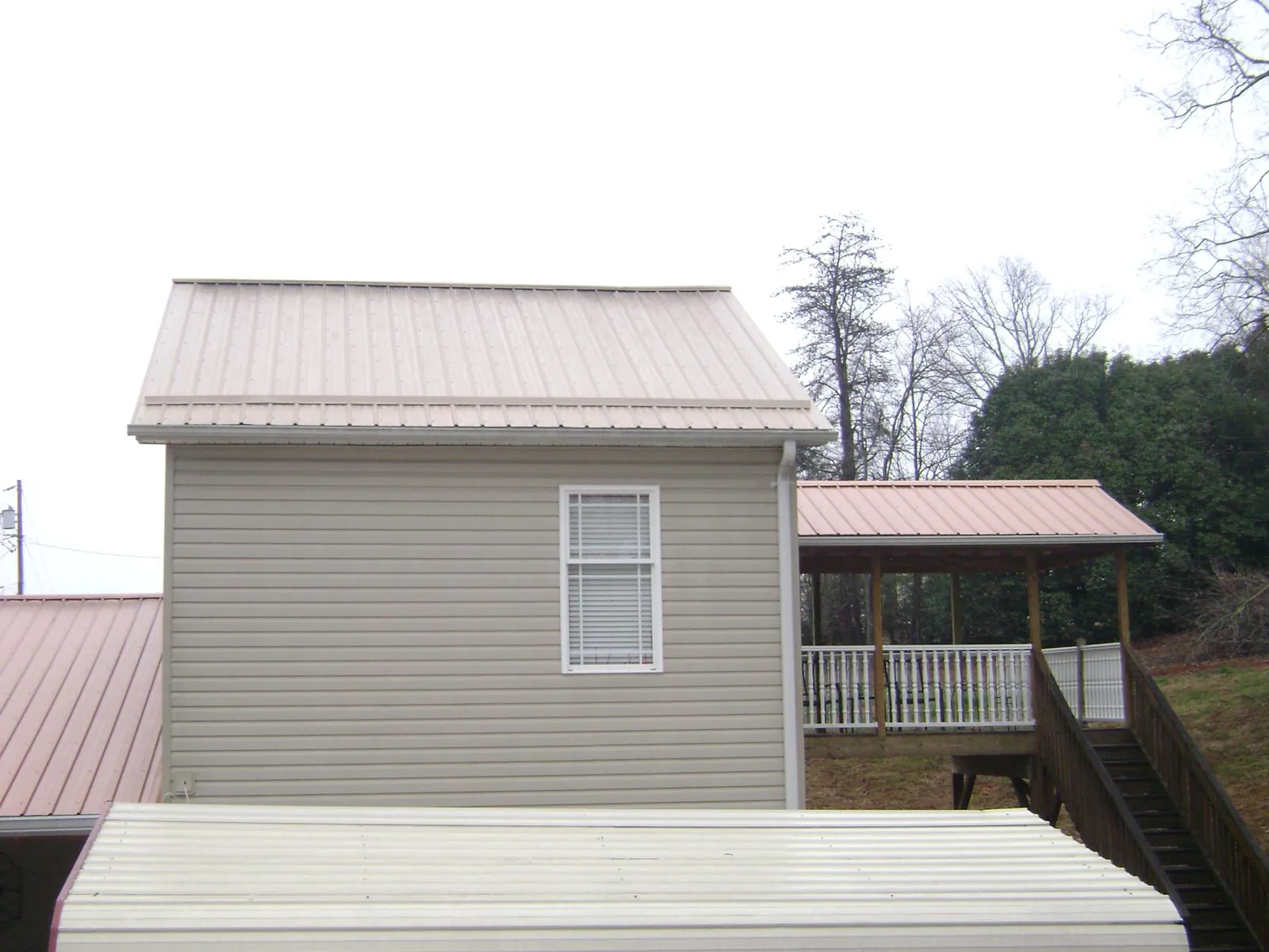 Tan metal roofs on a two story addition and attached porch in Berryville