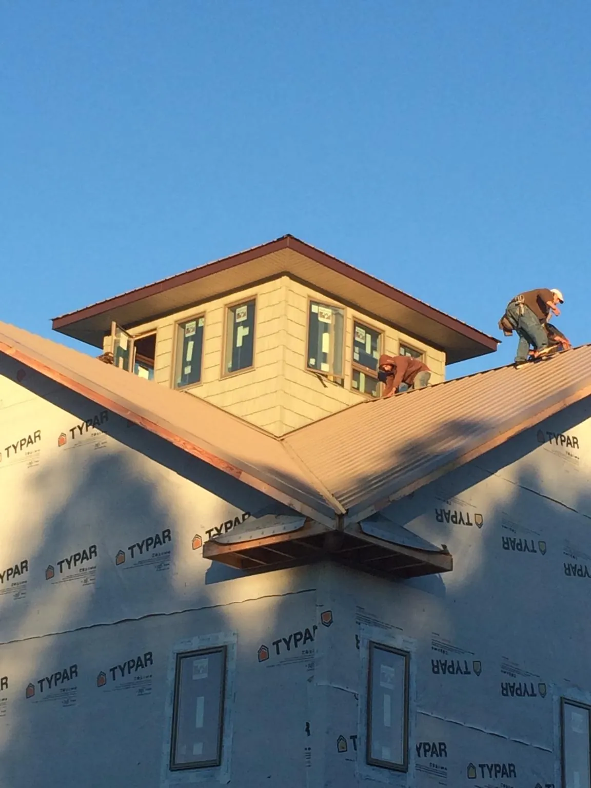 Roofers working around a rooftop cupola on a new metal roof at sunset — Roof Waterproofing in Berryville by Roofing Brothers